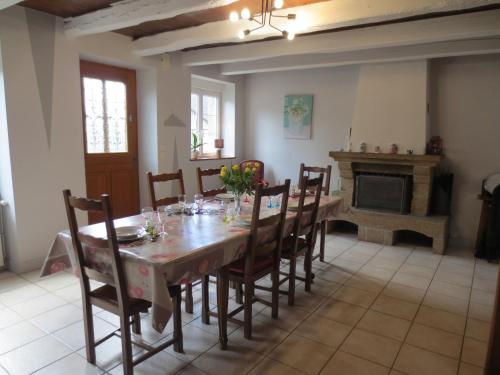 une salle à manger avec une table et des chaises et une cheminée dans l'établissement La Maison de Marie-Louise, à Saint-Martin-Landelles