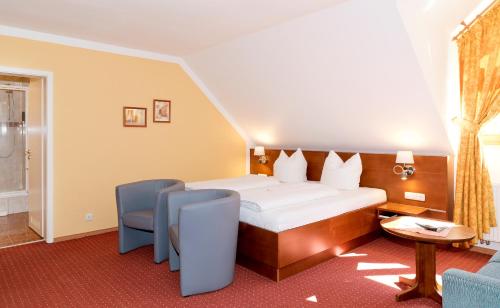 a hotel room with a bed and a table and chairs at Hotel am Katharinenholz in Potsdam