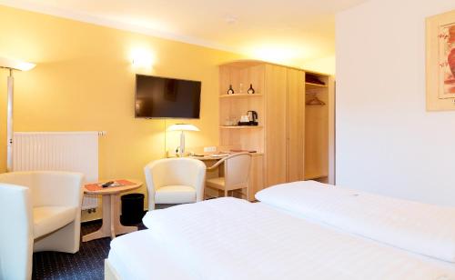 a hotel room with two beds and a desk at Hotel am Katharinenholz in Potsdam
