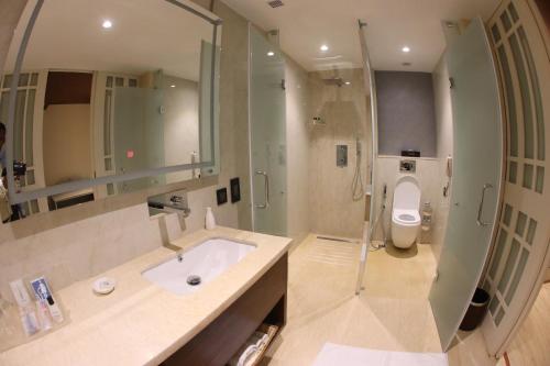 a bathroom with a toilet, sink, mirror and bathtub at Regenta Central RS Chennai OMR SIPCOT in Chennai