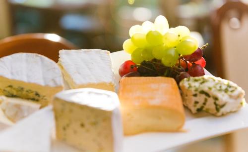 a table topped with different types of cheese and grapes at Hotel am Katharinenholz in Potsdam