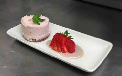 a pink cake and strawberries on a white plate at The Old Ginn House Inn in Great Clifton