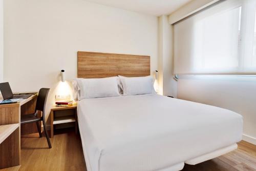 a bedroom with a large white bed and a desk at Sercotel Logroño Suites in Logroño