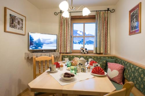 a dining room with a table and a television at ZITTRAUERHOF - Urlaub am Bauernhof Gastein in Bad Hofgastein