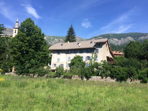 a large white house in a field with a church at Gîtes La Draperie in Beauvezer