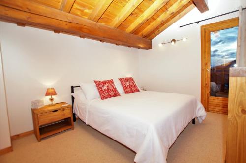 a bedroom with a white bed and a wooden ceiling at Chalet du Pre in Séez