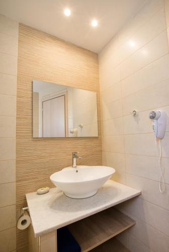 a bathroom with a white sink and a mirror at Porfyris Studios and Apartments in Karpathos Town