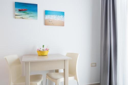 a white dining room table with white chairs and paintings at Porfyris Studios and Apartments in Karpathos Town