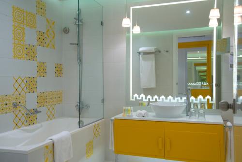 a bathroom with a tub and a sink and a mirror at Radisson Blu Resort & Thalasso Hammamet in Hammamet