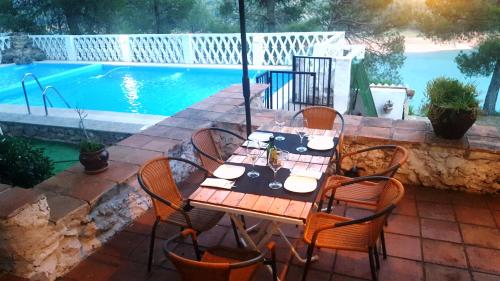 a wooden table and chairs next to a swimming pool at Casa Rural Los Parrales in El Tranco
