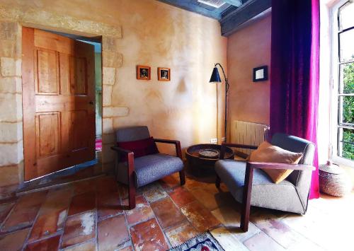 a living room with two chairs and a door at La Bastide du Farfadet in Laudun