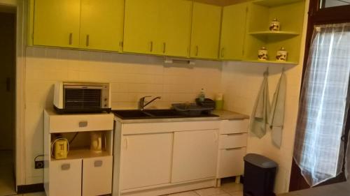 una pequeña cocina con armarios amarillos y microondas en Le Preia, en Prez-sur-Marne