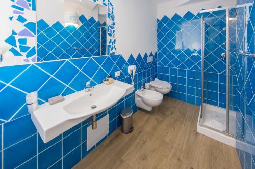 Olbia City Hotel في أولبيا: حمام من البلاط الأزرق مع حوض ومرحاض