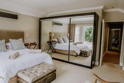 1 dormitorio con 2 camas y un espejo grande en Franschhoek Village House, en Franschhoek