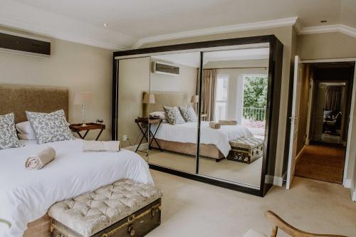 a bedroom with two beds and a large mirror at Franschhoek Village House in Franschhoek