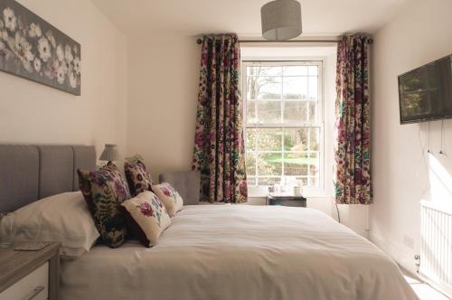 a bedroom with a bed and a window with curtains at Strathallan Guest House in Helston
