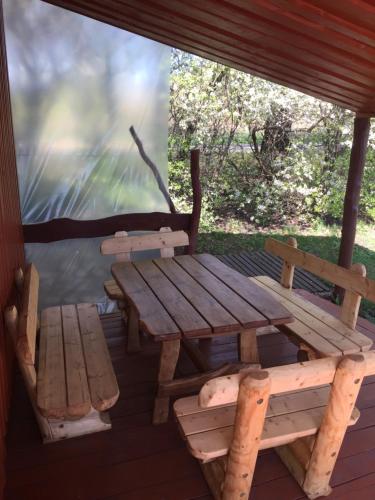 drewniany stół piknikowy i ławka na ganku w obiekcie Antano Razgaus kaimo turizmo sodyba w mieście Płotele