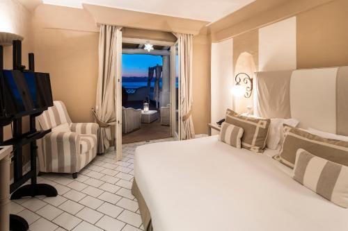 a hotel room with a bed and a view of the ocean at Therasia Resort Sea and SPA - The Leading Hotels of the World in Vulcano