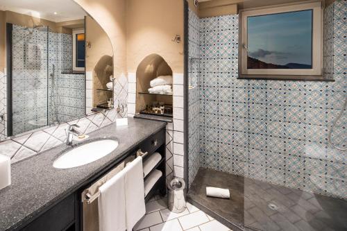a bathroom with a sink, mirror, and bathtub at Therasia Resort Sea and SPA in Vulcano