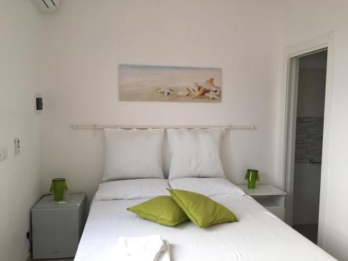 トッレ・ラピッロにあるSmile Affittacamereのベッドルーム1室(白いベッド1台、緑の枕2つ付)