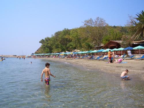 two boys are standing in the water at the beach at Hercules Sea Front Studios in Katelios