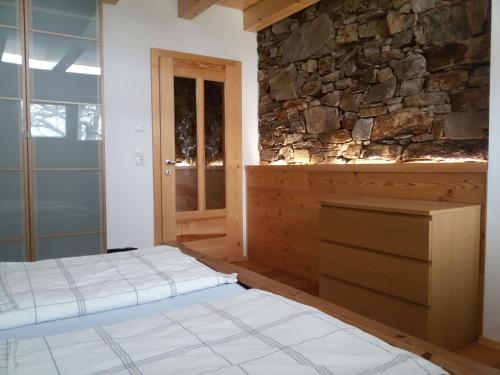 a bedroom with two beds and a stone wall at Ferienhaus Rustica in Rohrbach am Kulm