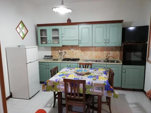 a kitchen with green cabinets and a table with chairs at Casa Vacanza NINA in Milazzo
