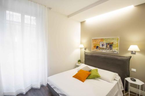 una camera da letto con un letto bianco con cuscini arancioni e verdi di Le Residenze a Firenze - Residenza de Boni Appartamento con vista Duomo a Firenze