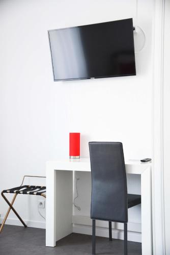 a white desk with a chair and a tv on a wall at Cit'Hôtel l'Europe - Cholet Gare in Cholet