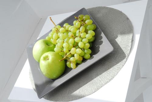 a plate of grapes and apples on a table at Archondoula Rooms in Plaka Milou