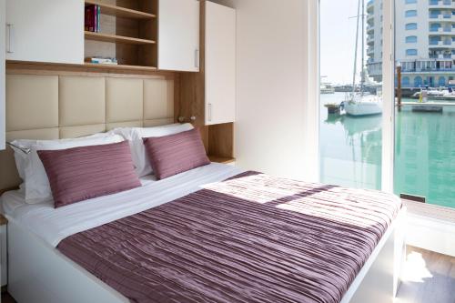 Bett in einem Zimmer mit einem großen Fenster in der Unterkunft Portoverde Luxury Houseboat in Misano Adriatico