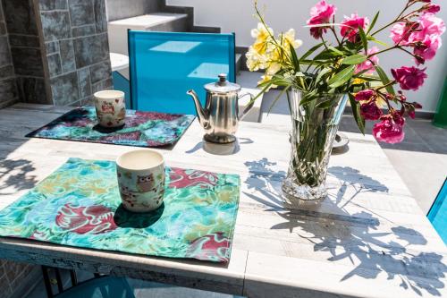 a table with cups and a vase of flowers on it at Adelphi Apartments in Perissa