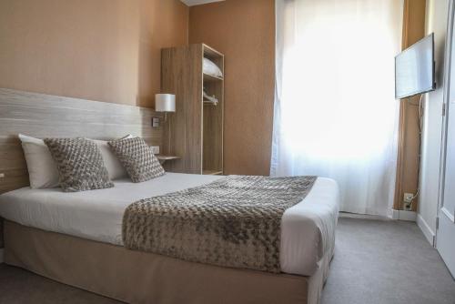 a bedroom with a large bed and a window at Cit'Hôtel l'Europe - Cholet Gare in Cholet