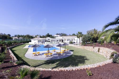 an aerial view of a house with a pool with umbrellas at Quinta do Rosal in Carvoeiro