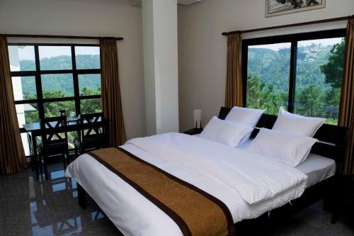 Un dormitorio con una cama con sábanas blancas y ventanas. en Da Blanche, en Shillong