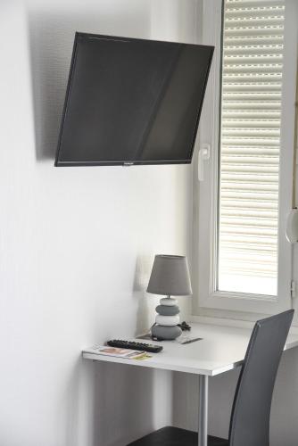 a desk with a lamp and a monitor on a wall at Cit'Hôtel l'Europe - Cholet Gare in Cholet
