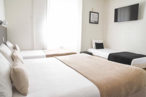a hotel room with three beds and a flat screen tv at Cit'Hôtel l'Europe - Cholet Gare in Cholet