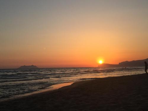 a person walking on the beach at sunset at Sperlonga By The Sea in Sperlonga