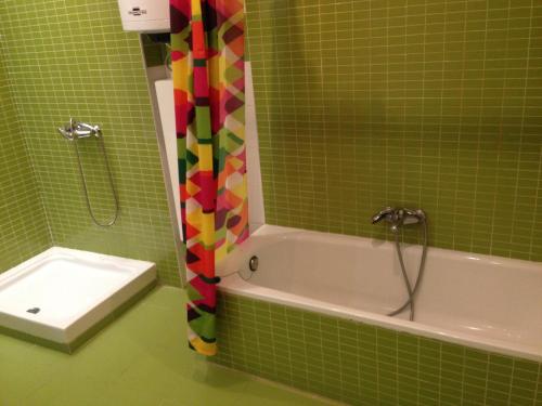 La salle de bains est pourvue de carrelage vert, d'une douche et d'une baignoire. dans l'établissement ap. con encanto, à Haro