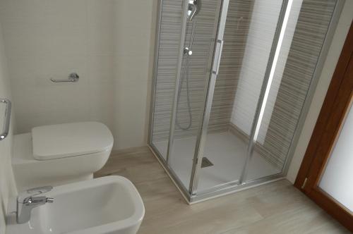 a white bathroom with a shower and a toilet at Casa Comisso in Caorle