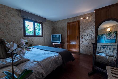 - une chambre avec un lit, un miroir et une télévision dans l'établissement Roque nublo rural houses I, à Vega de San Mateo