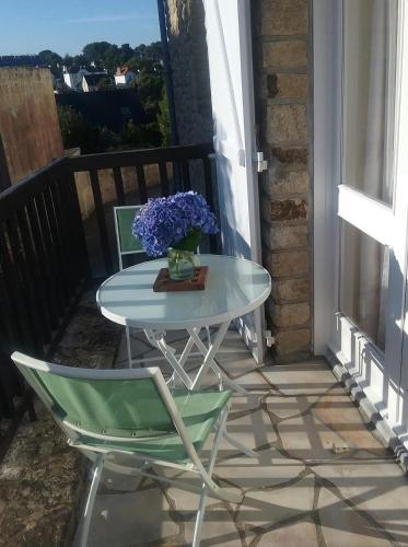 a table and chairs on a balcony with purple flowers at Studio La Trinité sur Mer in La Trinité-sur-Mer