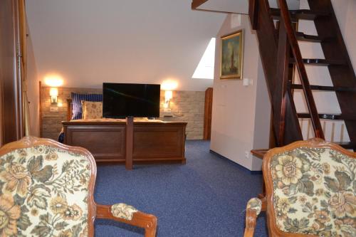 a living room with a flat screen tv and two chairs at Penzion Aurooms in Zlatníky