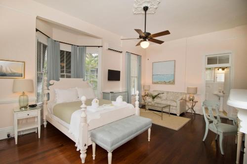 Un dormitorio con una cama blanca y una sala de estar. en The Conch House Heritage Inn, en Key West