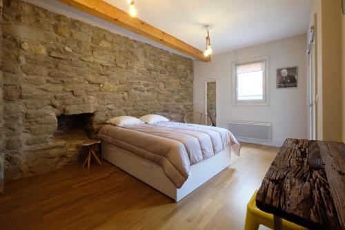 une chambre avec un mur en pierre et un lit dans l'établissement Mélina - appartement dans les remparts de la Bastide avec parking et terrasse, à Carcassonne