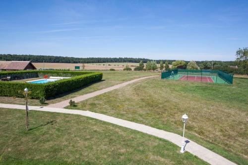 a field with a pool and a tennis court at Logis Le Fleuray in Cangey