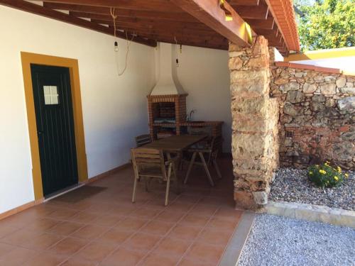 a patio with a table and a stone wall at Villa Rominha Alvaiázere - Casa do Rancho in Alvaiázere