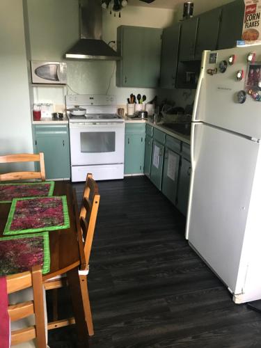 a kitchen with a white refrigerator and a table at Ranny's Private Rooms in Calgary