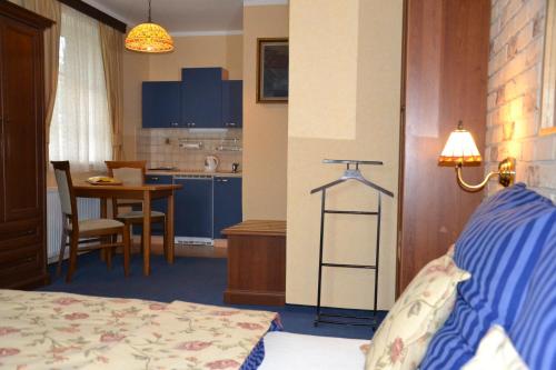 a bedroom with a bed and a kitchen with a table at Penzion Aurooms in Zlatníky