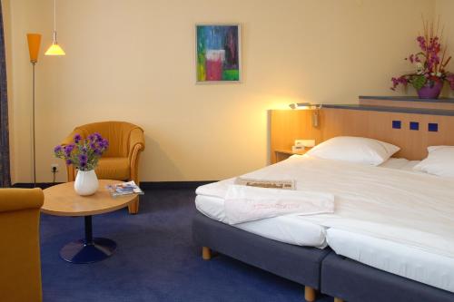 a hotel room with a bed and a table with flowers at Hotel Garni Lindacher Hof in Burghausen